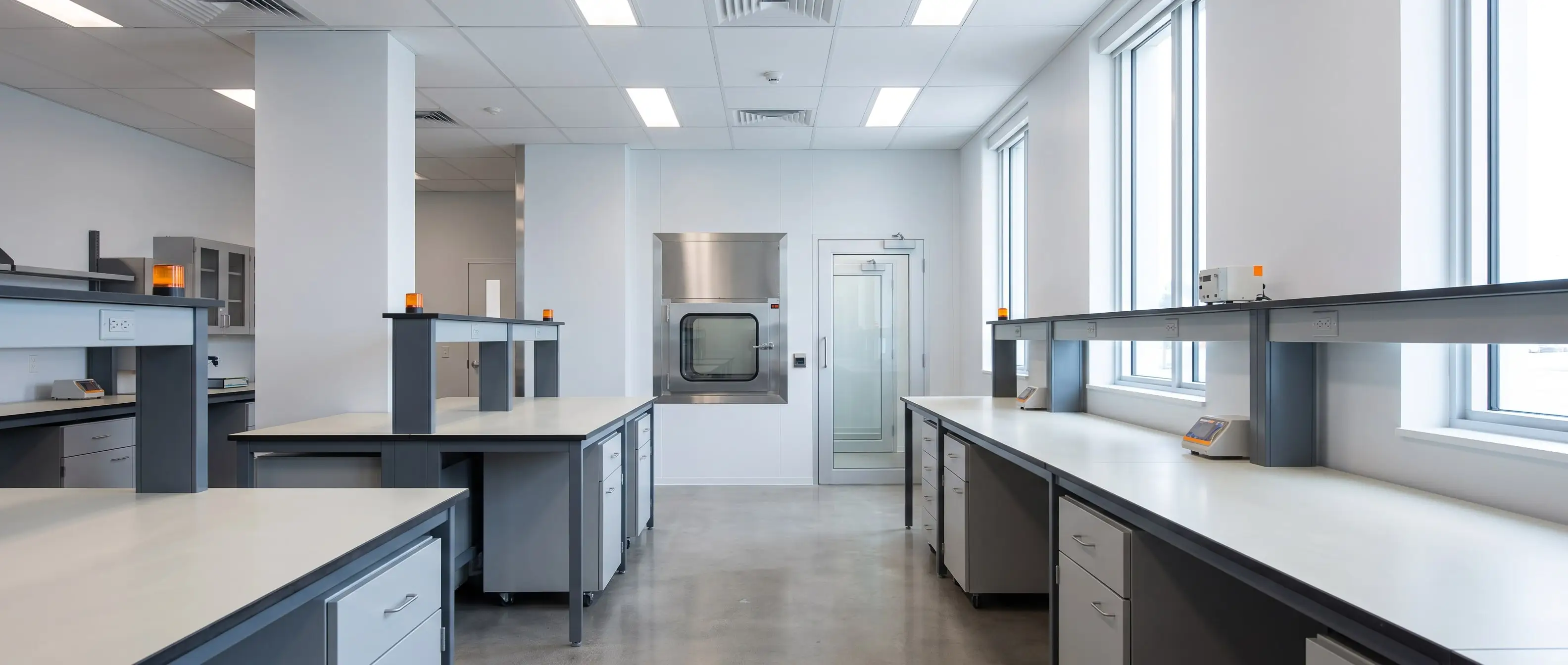 Laboratory corridor leading toward a cleanroom pass box, straight verticals, even daylight